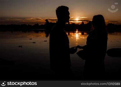 silhouette of loving couple hugging on the lake at sunset. Beautiful young couple in love walking on the shore of the lake at sunset in the rays of bright light. copy space. selective focus. silhouette of loving couple hugging on the lake at sunset. Beautiful young couple in love walking on the shore of the lake at sunset in the rays of bright light. copy space. selective focus.