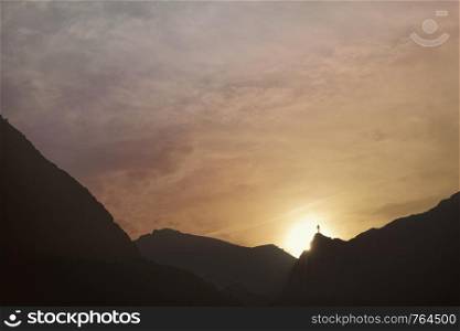 Silhouette of man at the top of the mountain on sunset. Mountain cascade