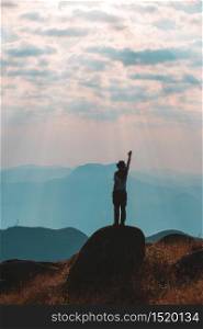 Silhouette of man hold up hands on the peak of mountain,success concept