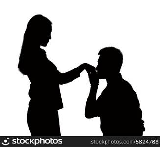 Silhouette of man on one knee, kissing woman&rsquo;s hand.