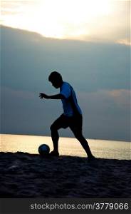 silhouette of man play soccer on the beach