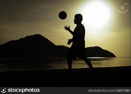 silhouette of man playing soccer on the beach