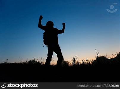 Silhouette of man with rised hands on dark sky
