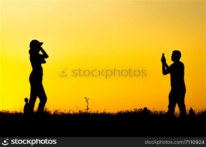 Silhouette of many tourists are taking pictures by smart phone on the top of the mountain during sunset times.