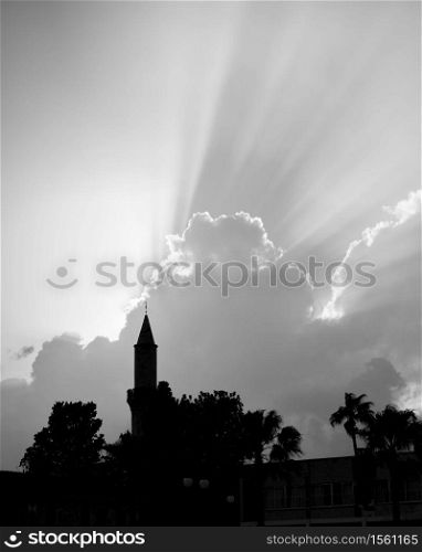 Silhouette of mosque with minaret and the sky with rays of light above, Black and white photography