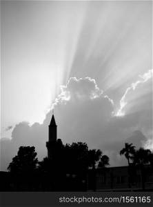 Silhouette of mosque with minaret and the sky with rays of light above, Black and white photography
