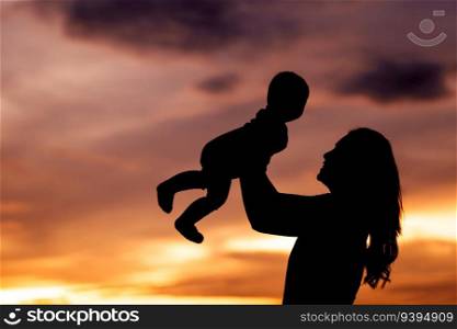 silhouette of mother holding and lifting with her infant baby at sunset