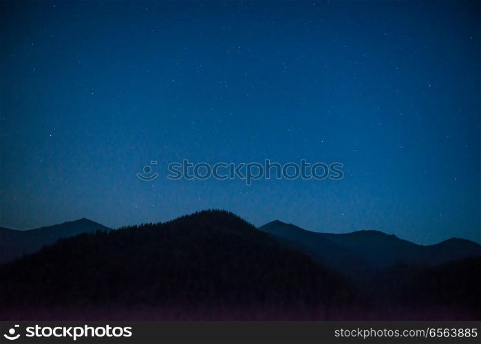 Silhouette of mountain range under dark blue night sky with many bright stars. Silhouette of mountain range at night