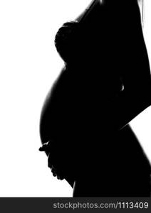 Silhouette of naked pregnant woman holding abdomen