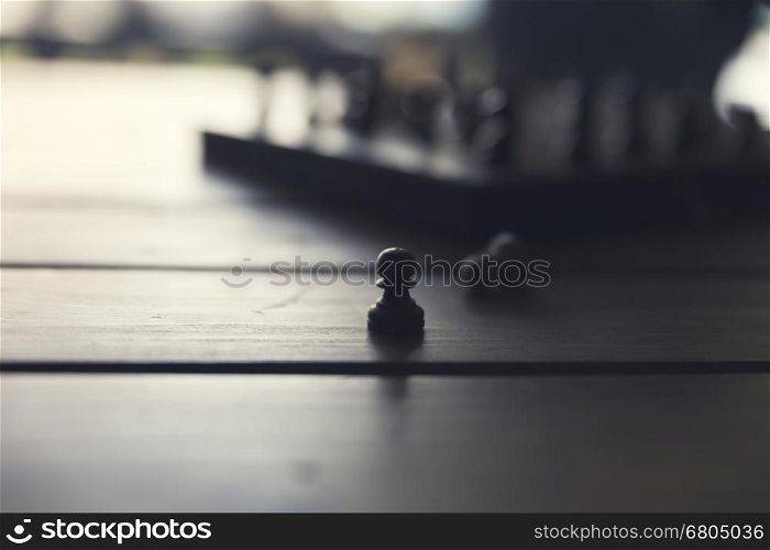 silhouette of pawn and chessboard game on wooden table, vintage tone and selected focus