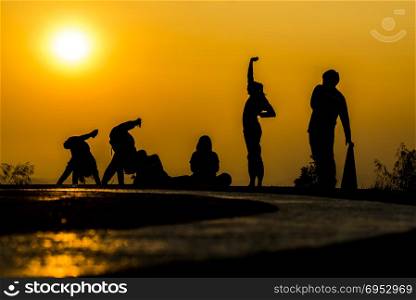 silhouette of people group practicing yoga on the beach at sunset