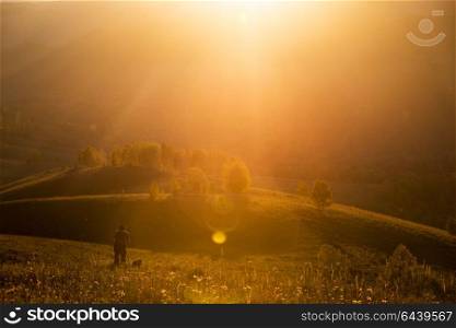 Silhouette of photographer on sunset. The man is taking a photograph in the Altay mountains in beauty summer day. Silhouette of photographer on sunset.