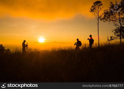 silhouette of photographer taking picture of landscape during sunset