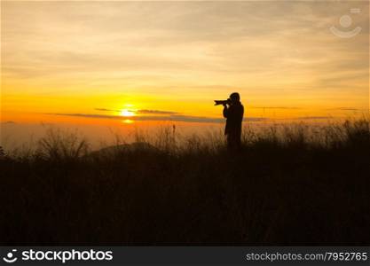 silhouette of photographer taking picture of landscape during sunset