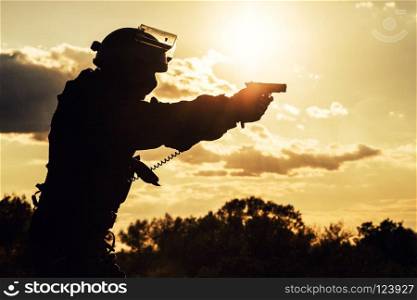 Silhouette of police officer with pistol at sunset