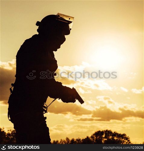 Silhouette of police officer with pistol at sunset