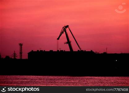 Silhouette Of port Crane In Front Of Red Sunset Sky, a lot of copyspace on the sky. Silhouette Of port Crane In Front Of Red Sunset Sky