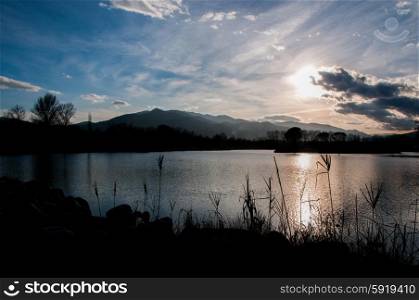 Silhouette of reeds and mountains by a lake