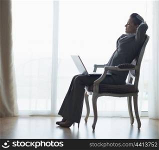 Silhouette of relaxed business woman sitting with laptop