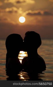 Silhouette Of Romantic Couple Standing In Sea