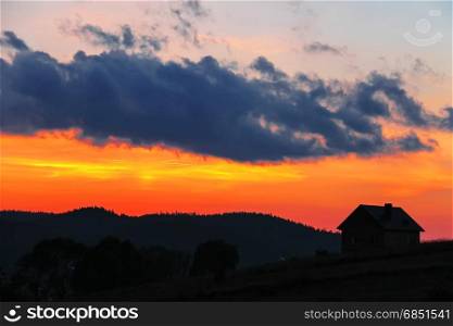 Silhouette of rural house on sunset sky background