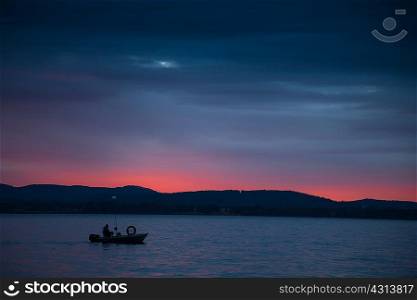 Silhouette of small boat on Lake Maggiore, Piedmont, Lombardy, Italy