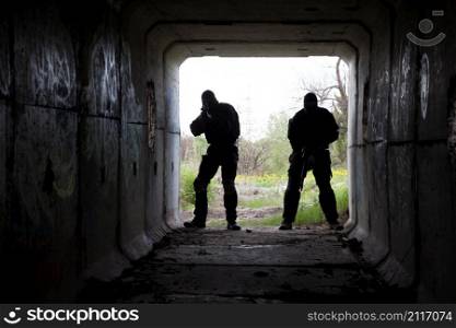 Silhouette of special forces operators with weapons in the tunnel. in the tunnel