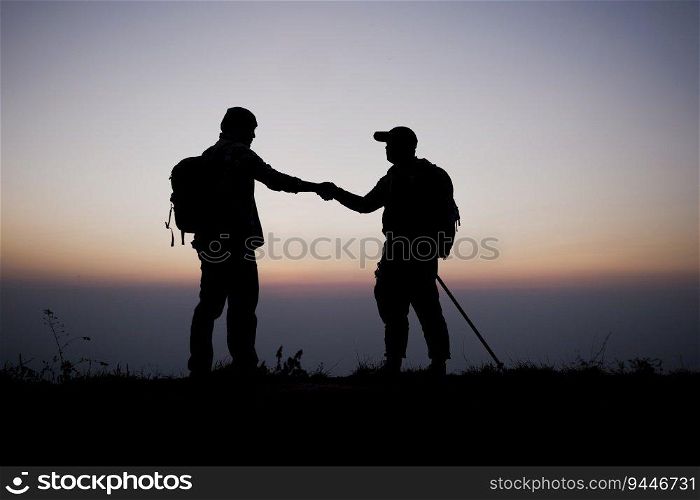 Silhouette of Teamwork helping hand trust help. Success in mountains. Hikers celebrate with hands up. Help each other on top of mountain and sunset landscape.