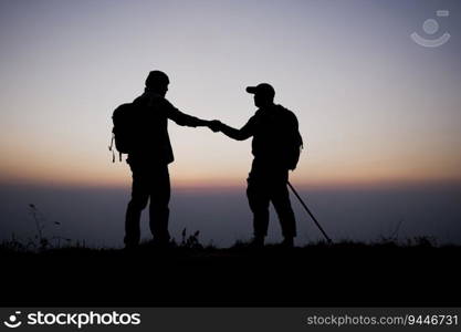 Silhouette of Teamwork helping hand trust help. Success in mountains. Hikers celebrate with hands up. Help each other on top of mountain and sunset landscape.