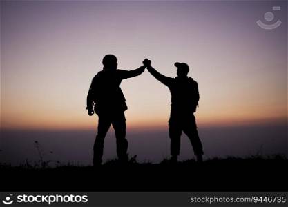 Silhouette of Teamwork helping hand trust help. Success in mountains. Hikers celebrate with hands up. Help each other on top of mountain and sunset landscape.