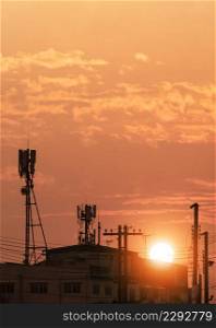 Silhouette of Telecommunication tower with antennas on top of building against sunset sky background in vertical frame