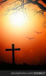 Silhouette of the cross and tree with blurred bird with flare at sunset.