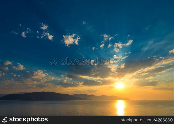 silhouette of the mountains and the morning sun over the sea