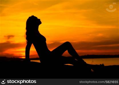 Silhouette of the pregnant lady sitting on the sand