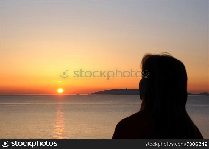 Silhouette of the woman looking at the rising sun on Crete island in Greece.