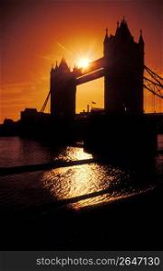 Silhouette of Tower Bridge and river with sunset in background, London, England