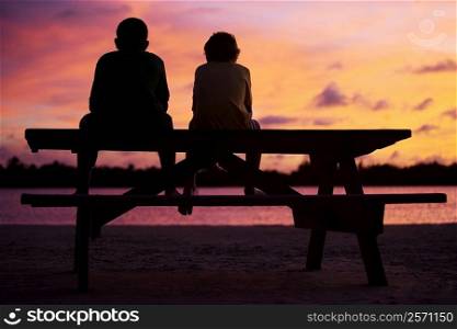 Silhouette of two boys sitting on a picnic table