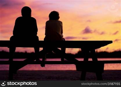 Silhouette of two boys sitting on a picnic table
