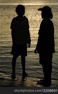 Silhouette of two boys standing on the beach