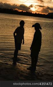 Silhouette of two boys standing on the beach