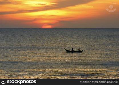 Silhouette of two people rowing a boat in the sea, Ko Lanta, Thailand