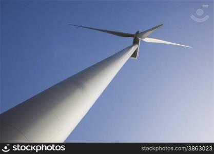 silhouette of wind turbine diagonally against blue sky