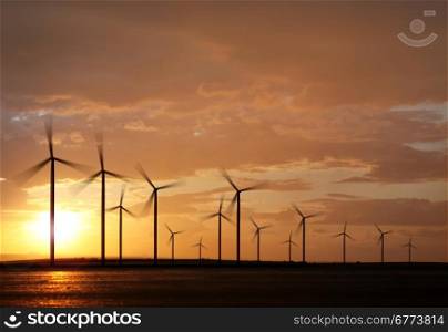 silhouette of wind turbine generating electricity on sunset