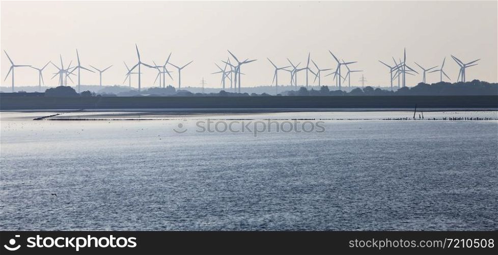 silhouette of wind turbine park on shore of north sea in german part ostfriesland seen from wadden sea