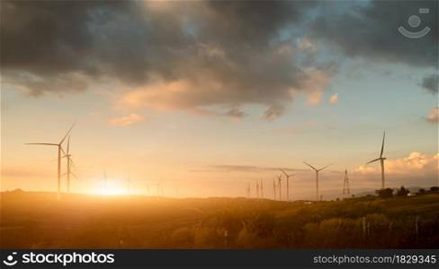 Silhouette of wind turbines. Beautiful view of wind generators in the mountain hill at sunset.