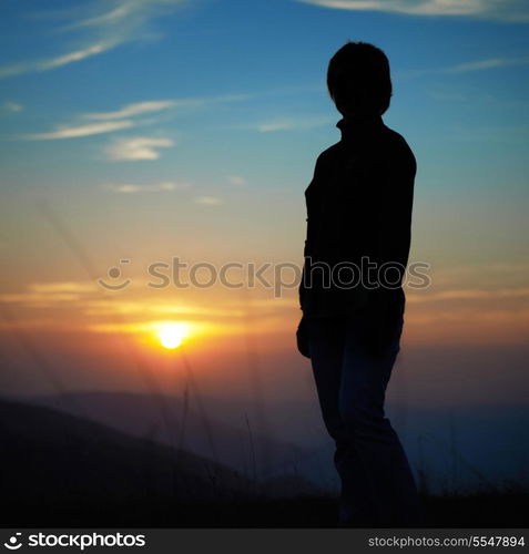 Silhouette of woman against sunset with orange clouds and sky