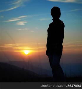 Silhouette of woman against sunset with orange clouds and sky