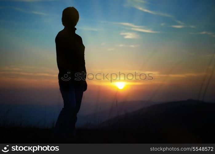 Silhouette of woman against sunset with orange clouds and sky