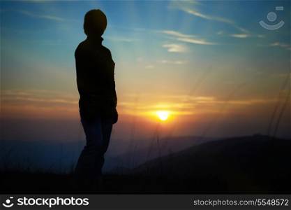 Silhouette of woman against sunset with orange clouds and sky