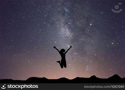 Silhouette of woman is jumping on top of mountain and milky way